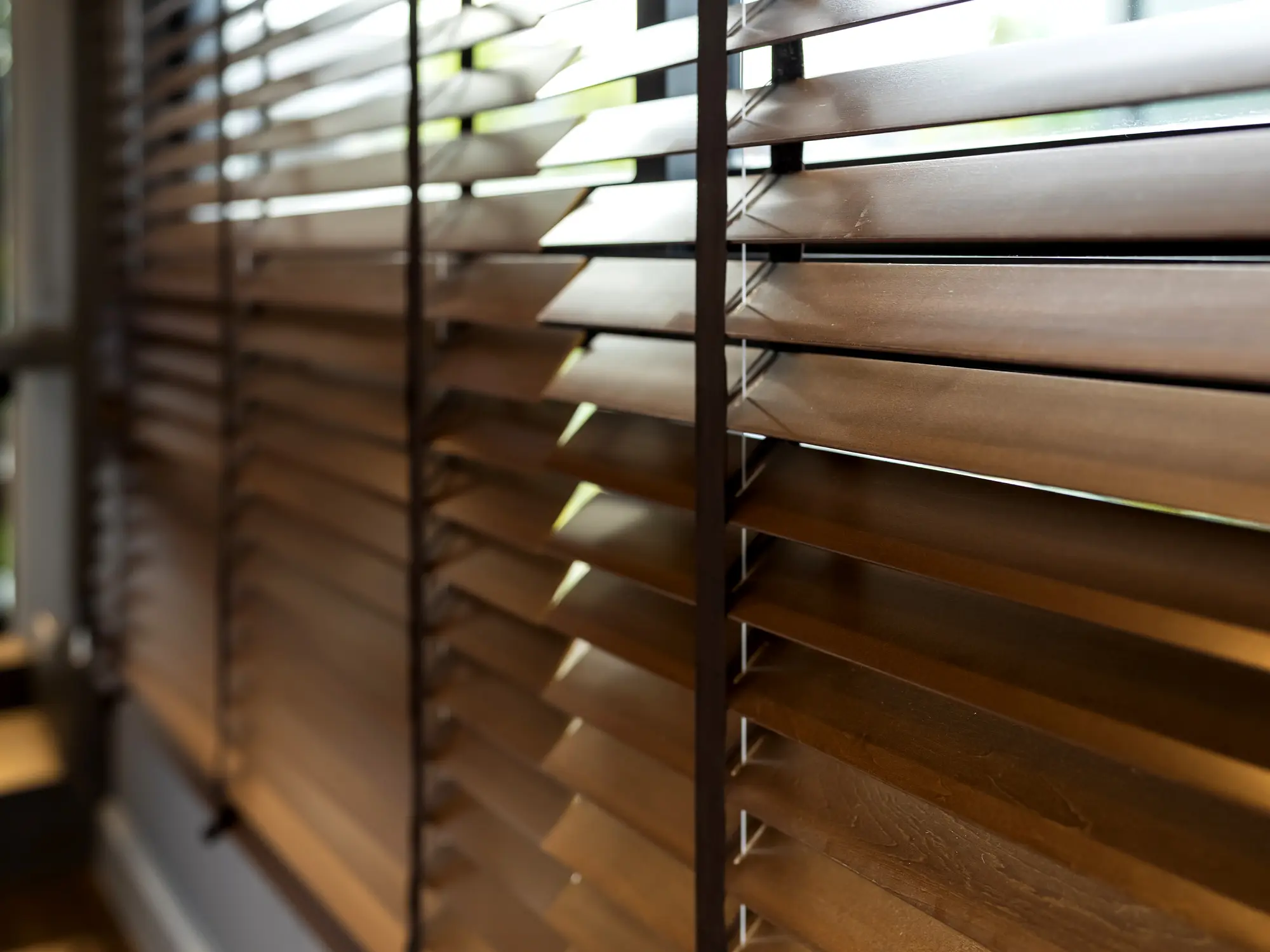 Close-up of wooden window blinds with light filtering through.