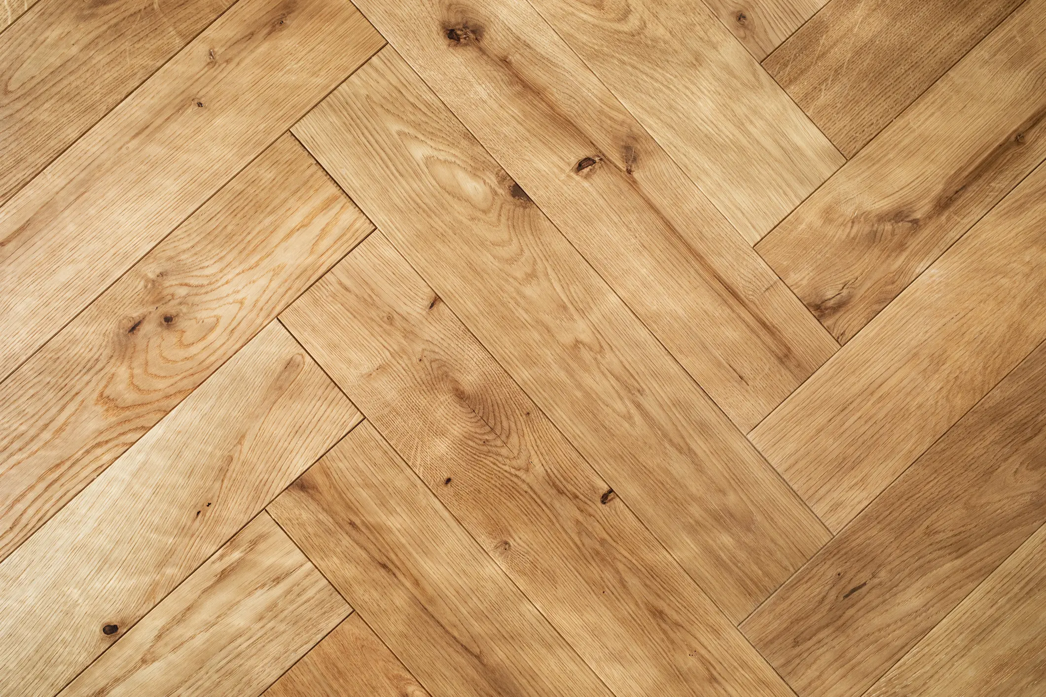 Close-up of wooden parquet flooring arranged in a herringbone pattern.