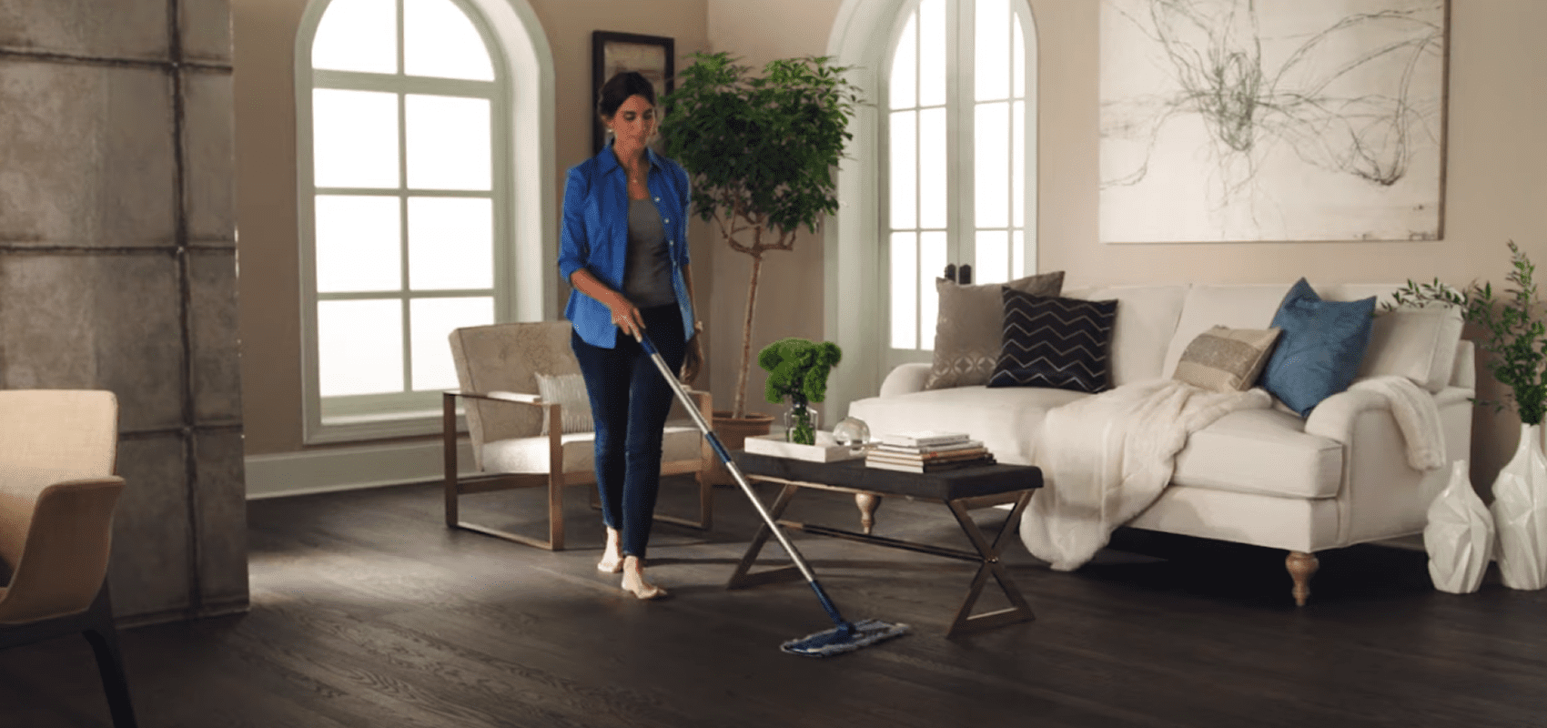 Woman vacuuming a modern living room with natural light.