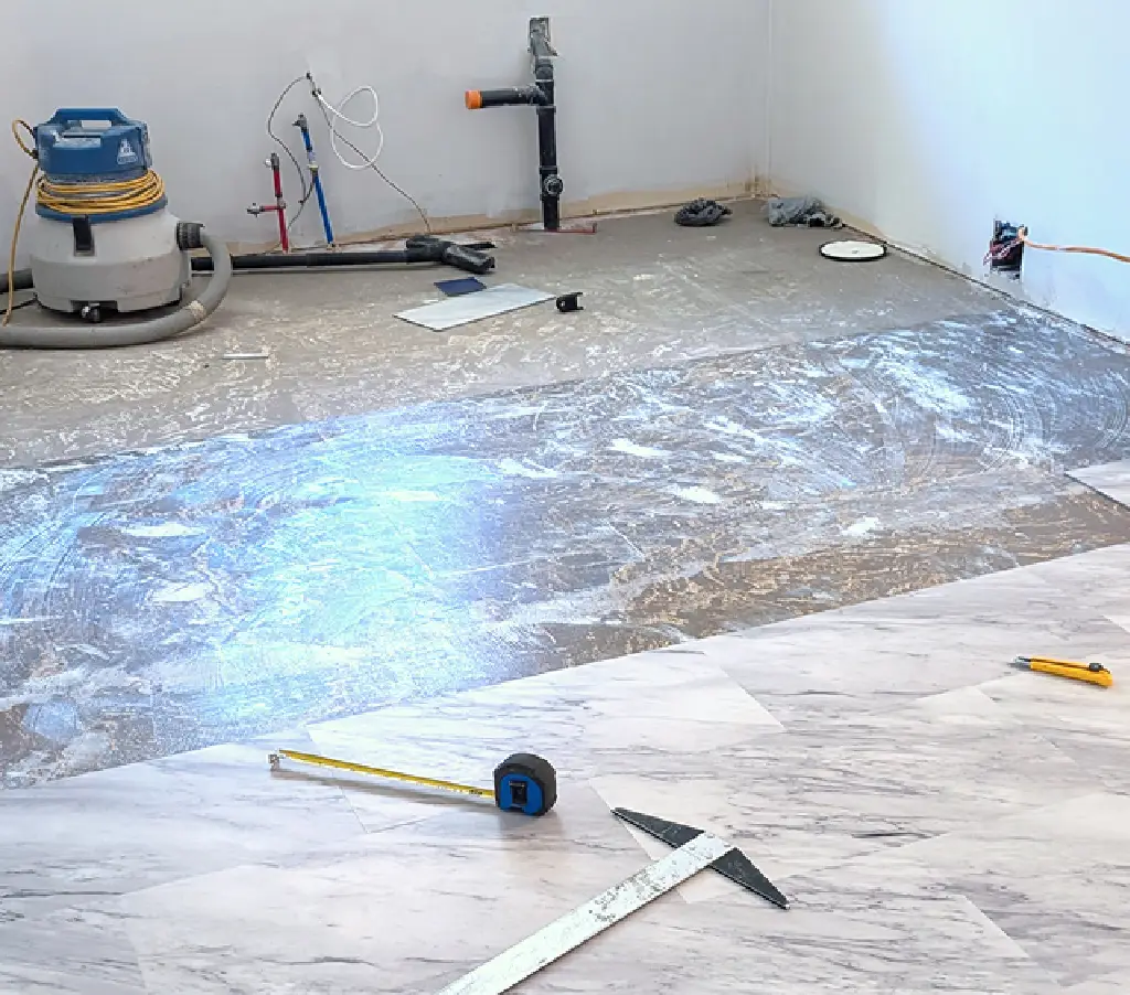 Floor tiles being installed in a room under renovation.
